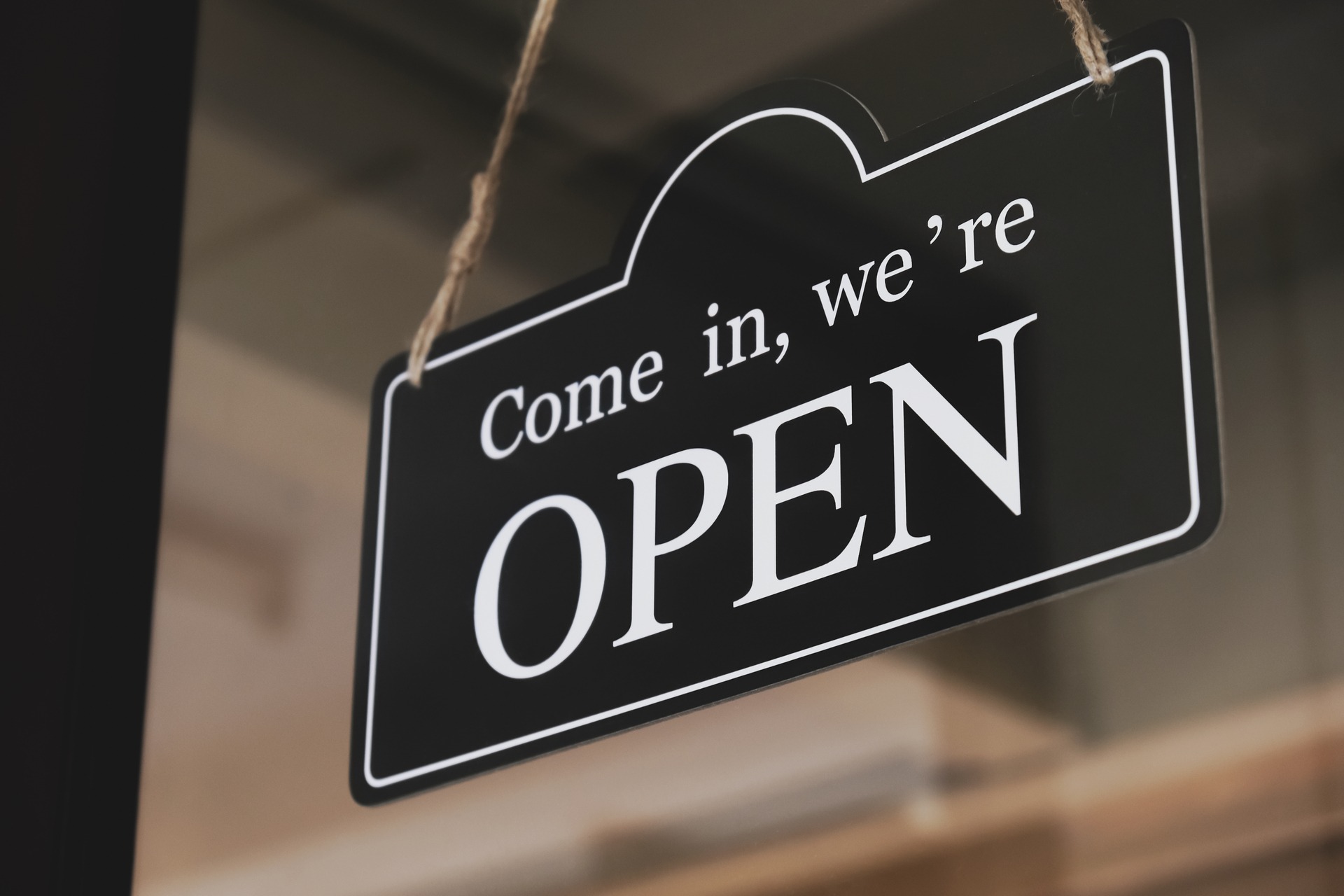 A sign that says come in we're open hanging on an office door.
