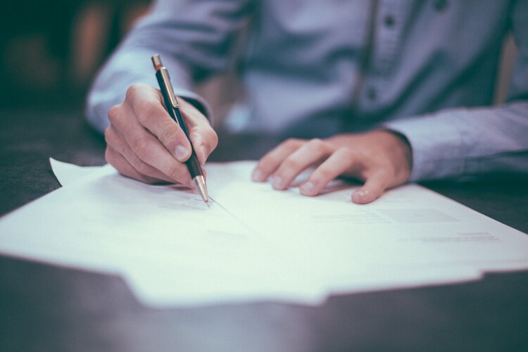 A man signing a document at Keller Almassian Law Office with a pen.